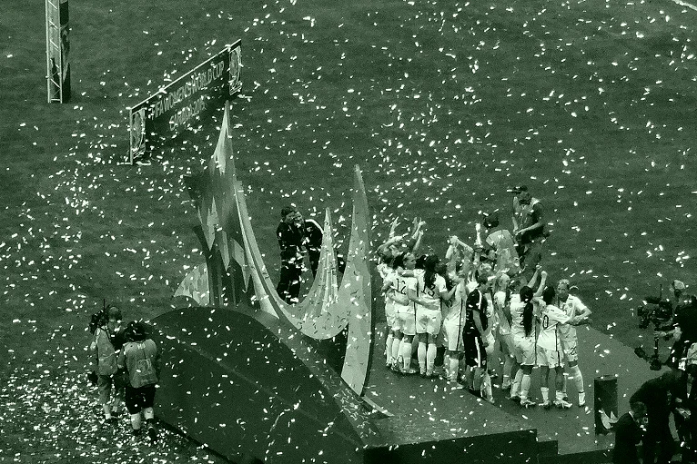 大型球场内夜色下人群与旗帜的画面(中场人数优势:德尚与吉瓦什的看管任务)